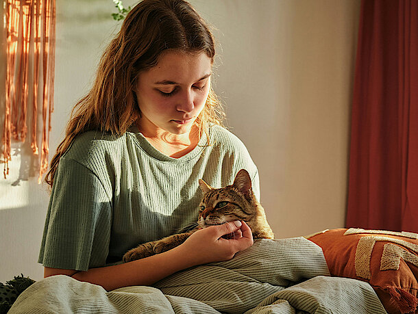 Katze kuschelt mit Frau im Bett