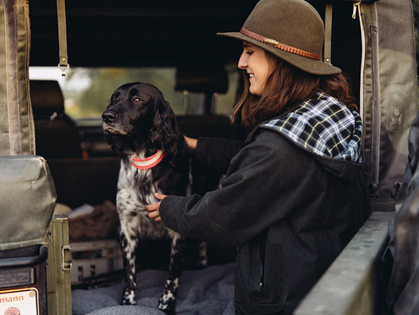 Jägerin mit ihrem Jagdhund am Fahrzeug
