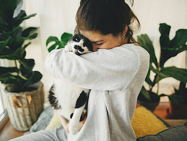 Katze kuschelt bei Frau auf dem Arm 