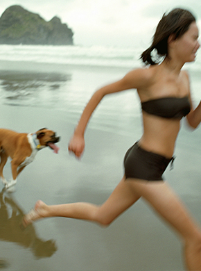 Frau joggt mit ihren Hund am Strand